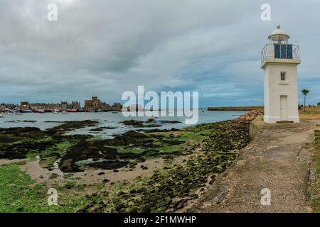 The Barfleur harbor lighthouse and port at low tide in the evening Stock Photo