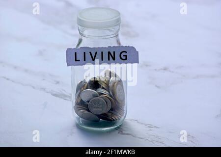 Blurred background of glass jar with multicurrency coins and text on white torn paper - Living Stock Photo