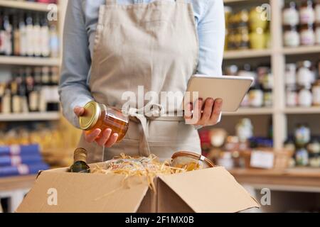 Close Up Of Female Owner Of Delicatessen Food Shop With Digital Tablet Preparing Online Grocery Order Stock Photo