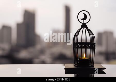 Lantern that have moon symbol on top with city background for the Muslim feast of the holy month of Ramadan Kareem. Stock Photo