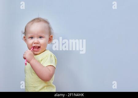 Toddler brushes his teeth against a light background. Copy space. Stock Photo