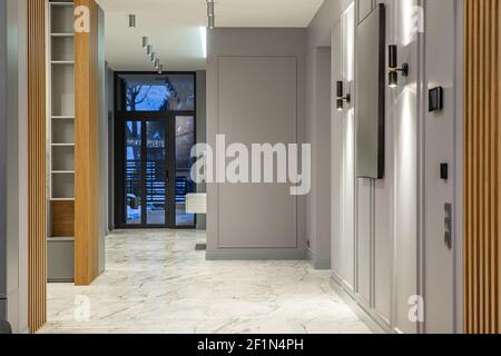 Interior of entrance hall in luxury privte house. Grey tones. Marble tile on floor. Wooden elements. Stock Photo