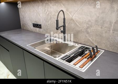 Modern interior of apartment. Luxury grey kitchen set. Huge sink. Built-in elements. Stock Photo