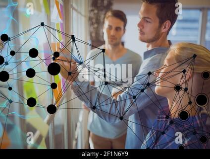 Network of connections against office colleagues writing on memo notes on glass board at office Stock Photo