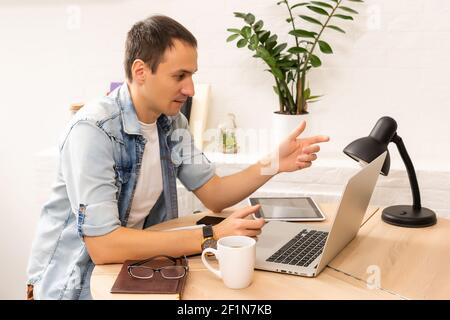 Focused young businessman holding video call with clients on laptop. Concentrated millennial man in glasses giving online educational class lecture Stock Photo