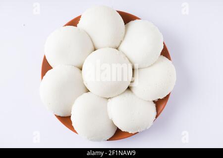 Idly or Idli, south indian main breakfast item which is beautifully arranged in an earthen ware with  white background. Stock Photo