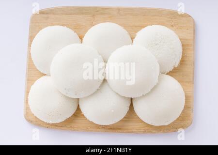 Idly or Idli, south indian main breakfast item which is beautifully arranged in a wooden base with white background. Stock Photo