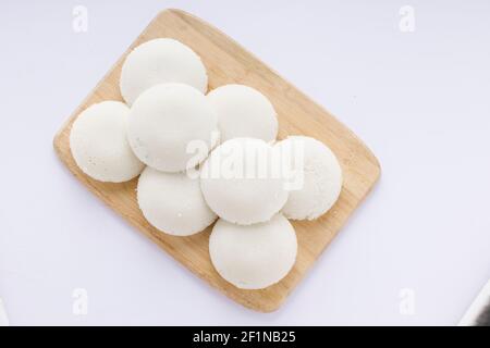 Idly or Idli, south indian main breakfast item which is beautifully arranged in a wooden base with white background. Stock Photo