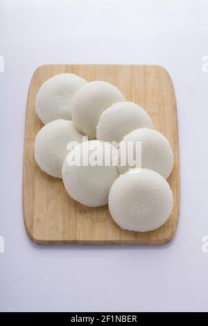 Idly or Idli, south indian main breakfast item which is beautifully arranged in a wooden base with white background. Stock Photo