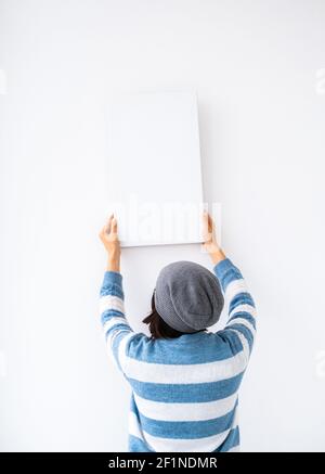 Girl holding blank canvas on white wall Stock Photo