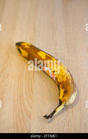 POZNAN, POLAND - Apr 01, 2016: Over ripe banana with brand sticker on wooden background Stock Photo