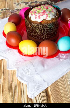 Glazed Easter cake on a red plate with colored eggs . Stock Photo