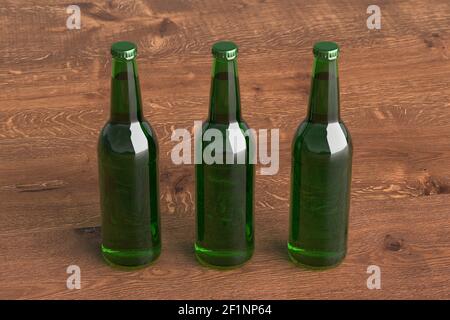 Three beer bottles 500ml mock up on wooden background. Side view Stock Photo