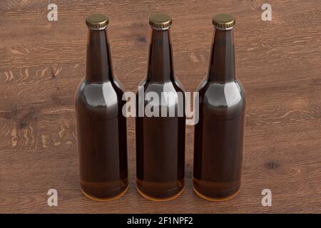 Three beer bottles 500ml mock up on wooden background. Side view Stock Photo