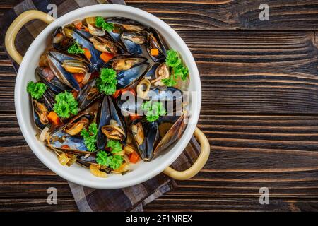 Boiled mussels in cooking dish with parsley on a wooden background Boiled mussels in cooking dish with parsley on a wooden background
