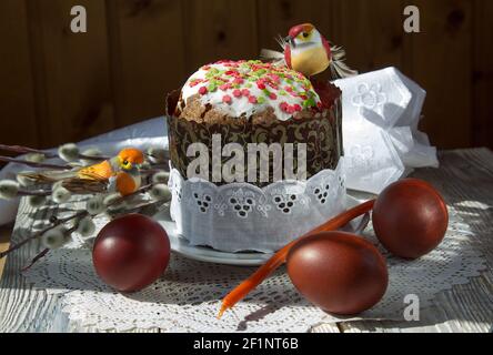 Easter cake with toy birds and painted eggs on a lace napkin. Stock Photo