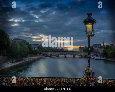 Sunrise over the river Seine in Paris France shows the lovers padlocks attached to the Pont des Arts bridge part of which recently collapsed due to th Stock Photo