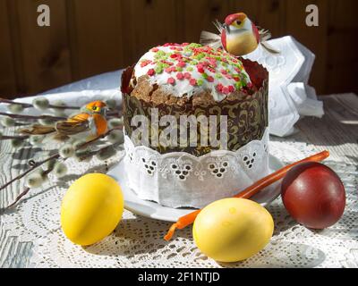 Painted eggs, toy birds, and an Easter cake on a lace napkin. T Stock Photo