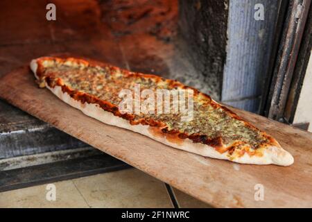 The Turkish pizza, called LAHMACUN, prepared with fresh minced meat and spices, is coming baked out of the stone oven Stock Photo