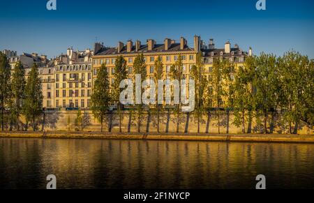 Morning sunlight reflects on a row of traditional houses on the banks of the river Seine in Paris France Stock Photo