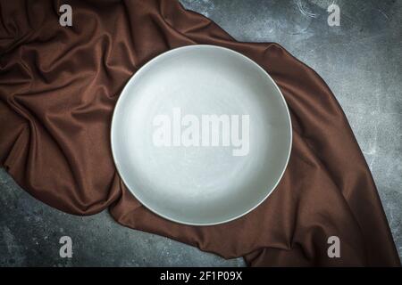 Empty plate on a dark background. Empty gray ceramic plate for food and dinner on a dark brown beautiful background. High quality photo Stock Photo