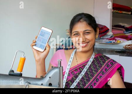 Indian woman textile worker showing mobile phone at workshop Stock Photo