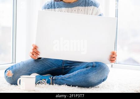 Girl sitting on floor holding white canvas Stock Photo