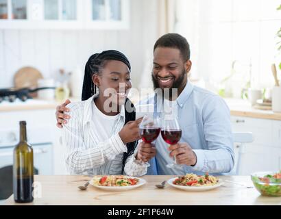 Millennial Couple's Lifestyle. Young Black Lovers Taking Photos On Smartphone While Having Date At Home, Happy African American Couple Drinking Red Wi Stock Photo