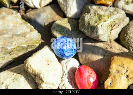 Easter eggs hidden between rocks, Colorful handmade painted Easter eggs hunt, Happy Easter Holiday concept in garden or park, Stock Photo