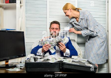 Bank assistant lady offers plastic card. Businessman with cash client of bank. Office manager administrator holds bank card. Credit loan and cash concept. Man business owner sit office pile of money. Stock Photo