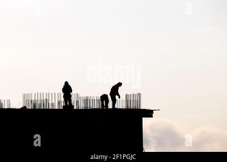 Silhouettes of workers on construction site against the sky. Housing construction, builders working on scaffolding Stock Photo