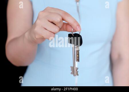 Real estate agent, apartment keys in female hand. Woman in blue dress, concept of purchase or rental home Stock Photo
