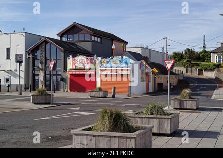 BRAY, IRELAND - Mar 16, 2020: Street view of local ice cream shops with closed shutters during COVID-19 lockdown. Empty crossroad at the front. Sunny Stock Photo