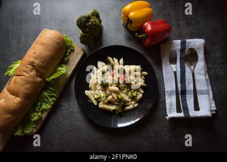 Popular Italian dish cheese penne pasta and bread loaf Stock Photo