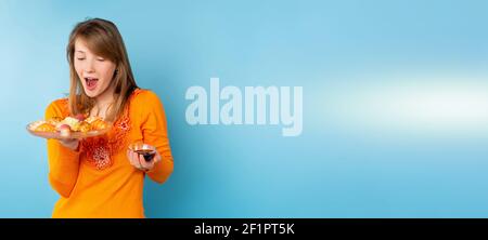 Banner, long format. An amazed woman eating sushi set, light blue background, blonde holding say sauce on a blue background Stock Photo