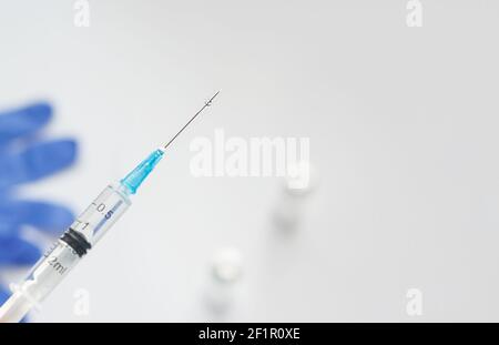 Disposable syringe with coronavirus vaccine with drop on a needle. Covid 19 vaccination concept. Stock Photo