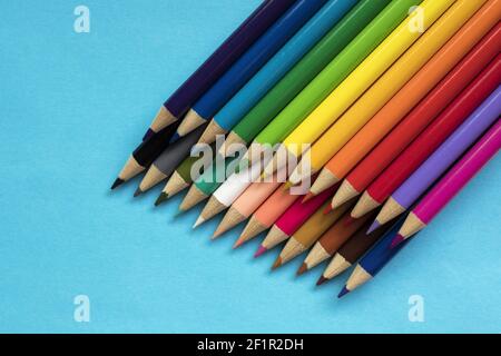 Multi colored pencils on blue paper background. Stock Photo