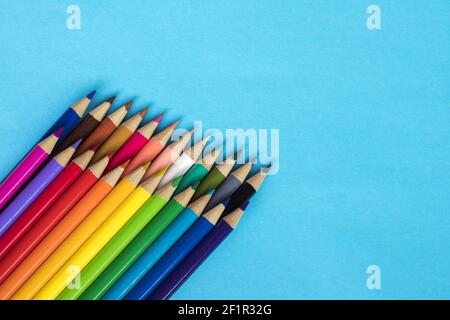 Multi colored pencils on blue paper background. Stock Photo