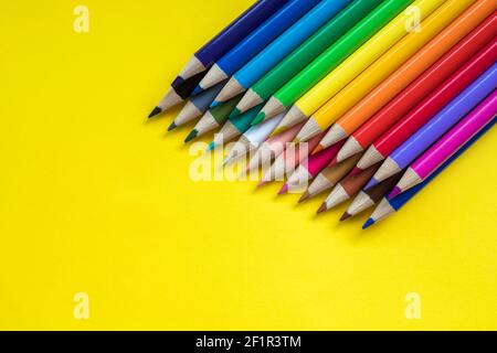 Colored pencils on yellow background with copy space for text on one side Stock Photo
