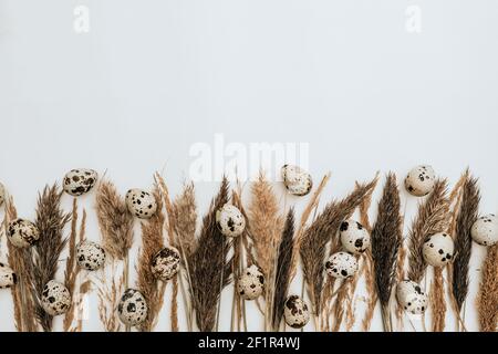 Reeds foliage branches bouquet with eggs on neutral white background. Flat lay, top view. Easter concept Stock Photo