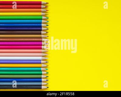 Colored pencils on yellow background with copy space for text on one side Stock Photo