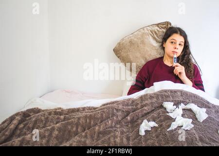 sick young woman with thermometer lying in bed Stock Photo