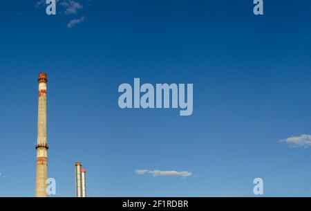 large blue pipe releases white steam into the blue sky, space for text, copy space. Close-up on a dramatic sky background Stock Photo