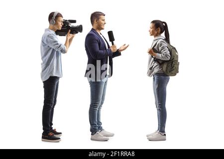 Full length profile shot of a reporter with a microphone and a cameraman interviewing a female student isolated on white background Stock Photo