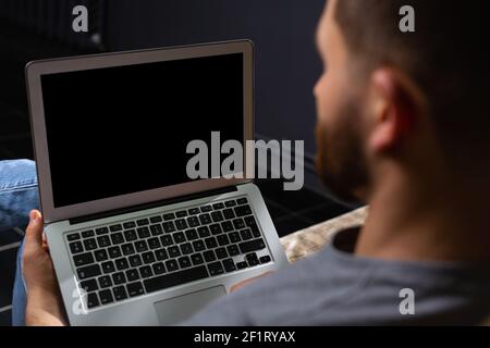 Cropped back photo of young male programmer working at home using laptop. Work from home. Telework. Stock Photo
