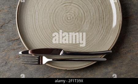 Plate, knife and fork on stone background Stock Photo