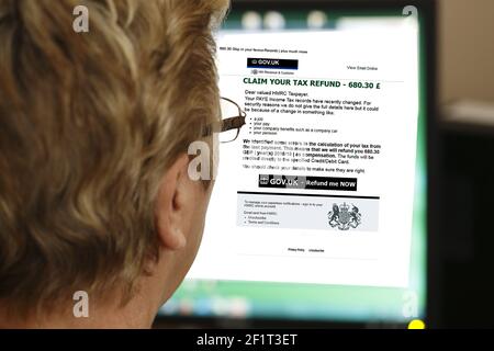 A woman reading a phishing email claiming that she is entitled to a tax refund. (UK). Editorial only Stock Photo