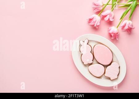 Easter table setting with floral decor and plate with easter gingerbread on pink table. Elegance dinner. Mock up. Top view. Stock Photo