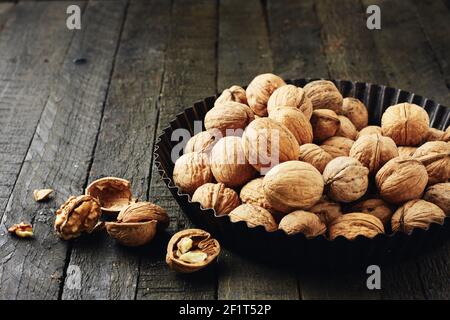 Whole walnuts and kernels on a dark wooden table. Stock Photo