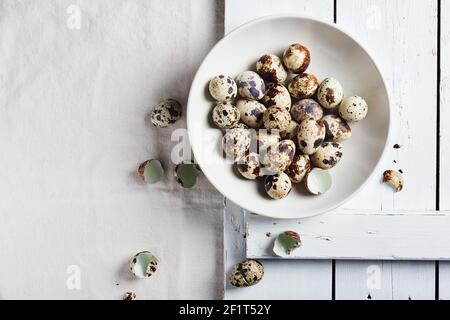 Quail eggs in a bowl on a white table, top view. Stock Photo